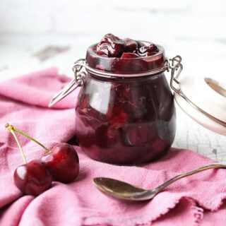 cherry compote in jar with spoon and cherries